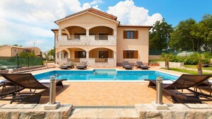 A two-story house with a swimming pool, outdoor seating, and a stone facade. - Beautiful modern villa in a small village near the sea (Trget)