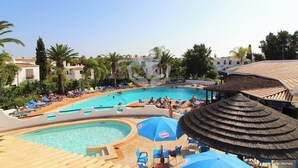 A resort pool area with multiple swimming pools, lounge chairs, umbrellas, and palm trees. - 2 Bedroom Apartment with Swimming Pool at São Rafael Beach - Albufeira (Albufeira)