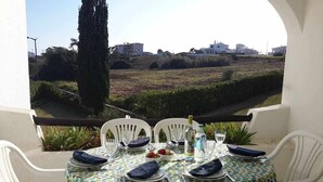 A table set for four with a view of a landscaped area and buildings in the background. - 2 Bedroom Apartment with Swimming Pool at São Rafael Beach - Albufeira (Albufeira)