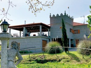 A stone building with a tower, a covered patio, and a statue in the foreground.