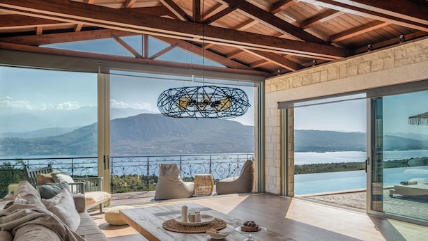 A spacious room with a large window overlooking a mountainous landscape and a pool.