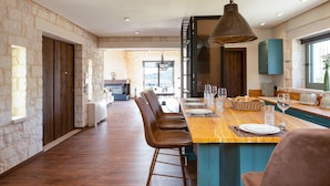 A spacious kitchen with a long island, wooden bar stools, and a large pendant light.