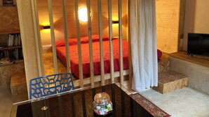 Una habitación acogedora con una cama, una mesa y un tarro de cristal, y un televisor.