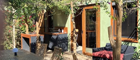 Un patio con una mesa y sillas, un sofá, y una pérgola de madera con plantas trepadoras.