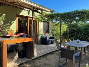 Une terrasse en bois avec des meubles d’extérieur, une pergola et une vue sur un bâtiment écologique.