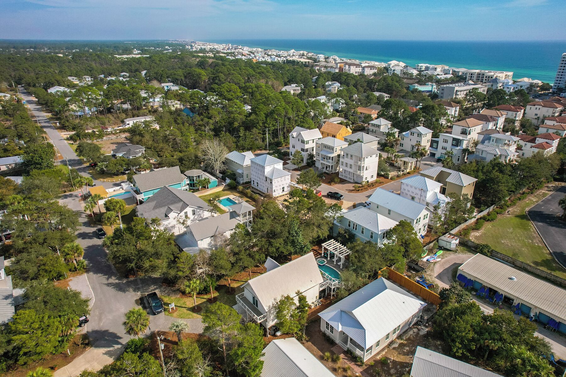 A residential area with houses, a swimming pool, and a view of the ocean.