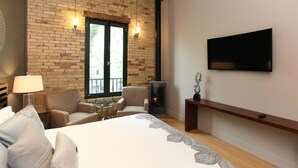 Un dormitorio con pared de ladrillo, chimenea, televisor, sofá y cama.