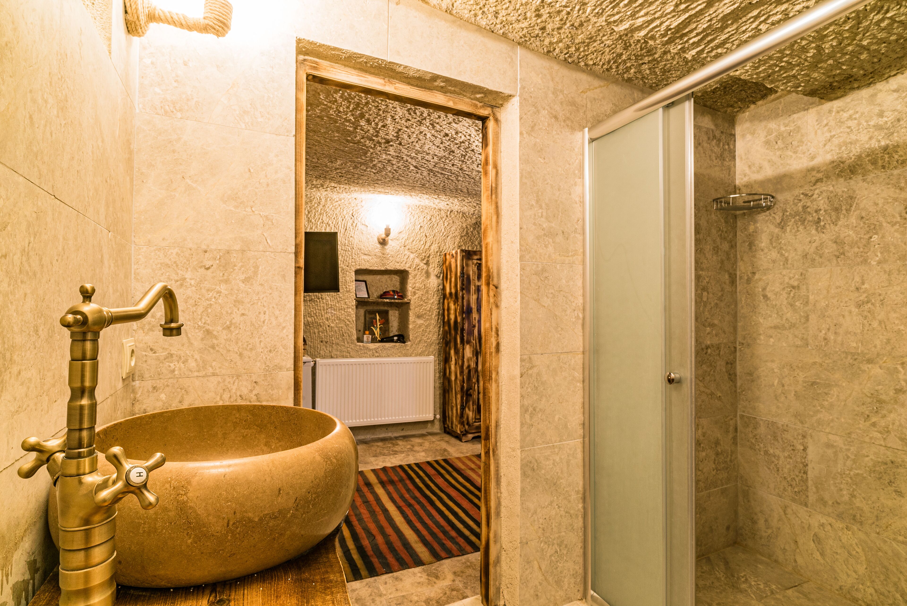 A bathroom with a large, round, beige sink, a vintage-style faucet, and a shower area with a glass door.