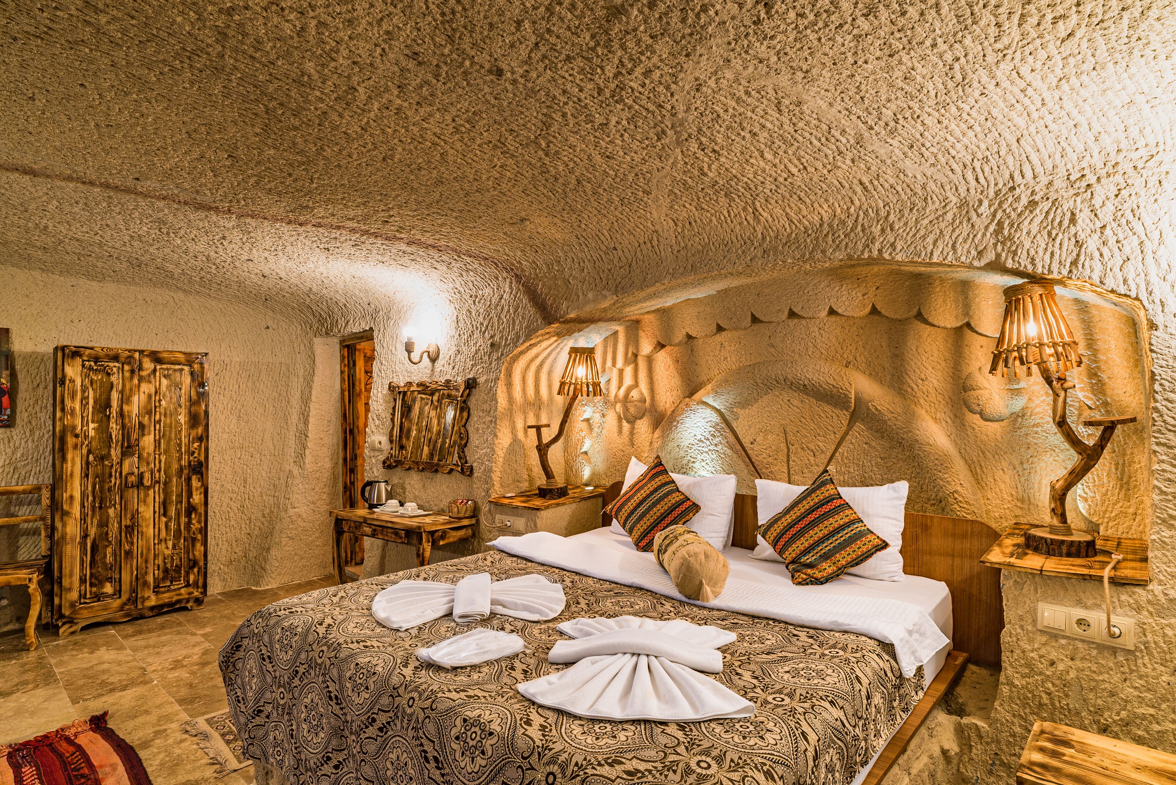 A room with a large bed, wooden headboard, and a textured ceiling.