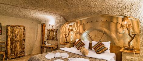 A room with a large bed, wooden headboard, and a textured ceiling.