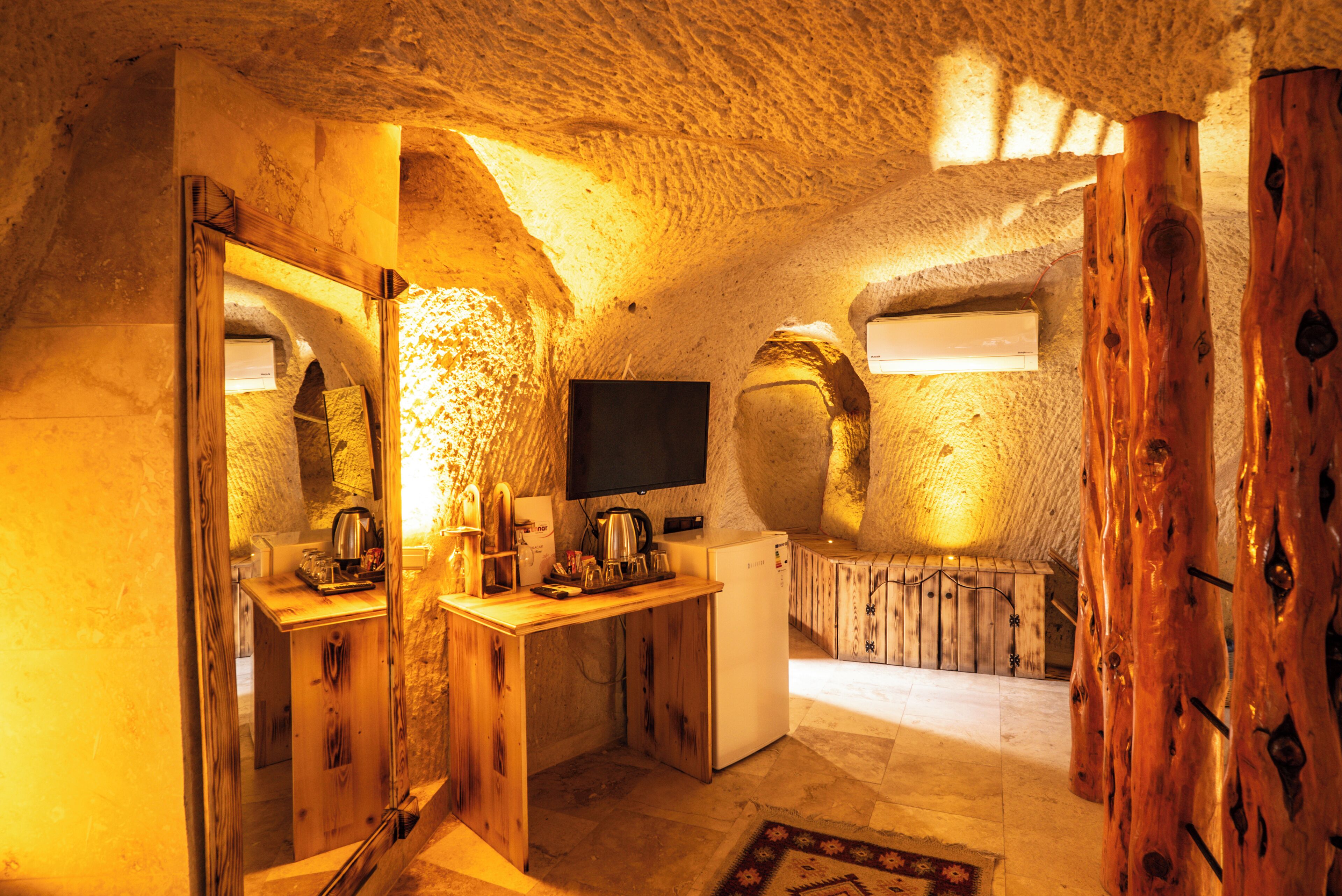 An interior with a wooden desk, a flat-screen TV, and a stone wall.