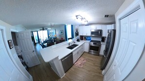 Een moderne keuken met witte kasten, roestvrijstalen apparatuur en een groot eiland.