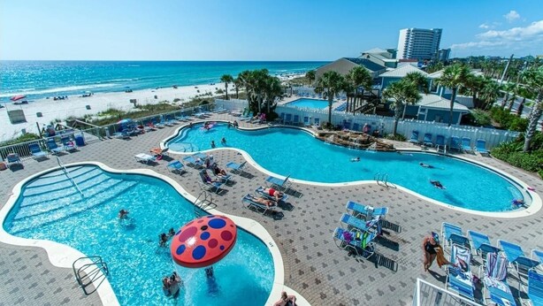 Een resort met meerdere zwembaden, een strand en uitzicht op de oceaan.