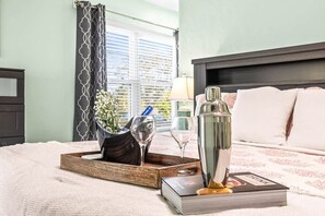 A neatly arranged bedroom with a bed, bedside table, lamp, and a window with curtains.