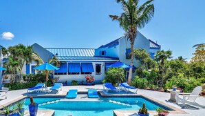 A pool area with lounge chairs, umbrellas, and potted plants. - Grace Bay Beach Ocean Villas, Oleander Villa. Rated #1 On Trip Advisor. (Providenciales)
