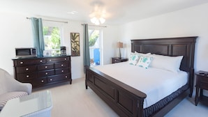 A bedroom with a large bed, a dresser, a chair, and a desk. - Grace Bay Beach Ocean Villas, Oleander Villa. Rated #1 On Trip Advisor. (Providenciales)
