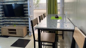 Un coin repas comprenant une table, des chaises, un téléviseur et un petit meuble.