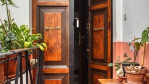 A wooden door with a metal handle, a welcome mat, and potted plants. - URBANA 37 MAISON   RIONE MONTI. (Roma)