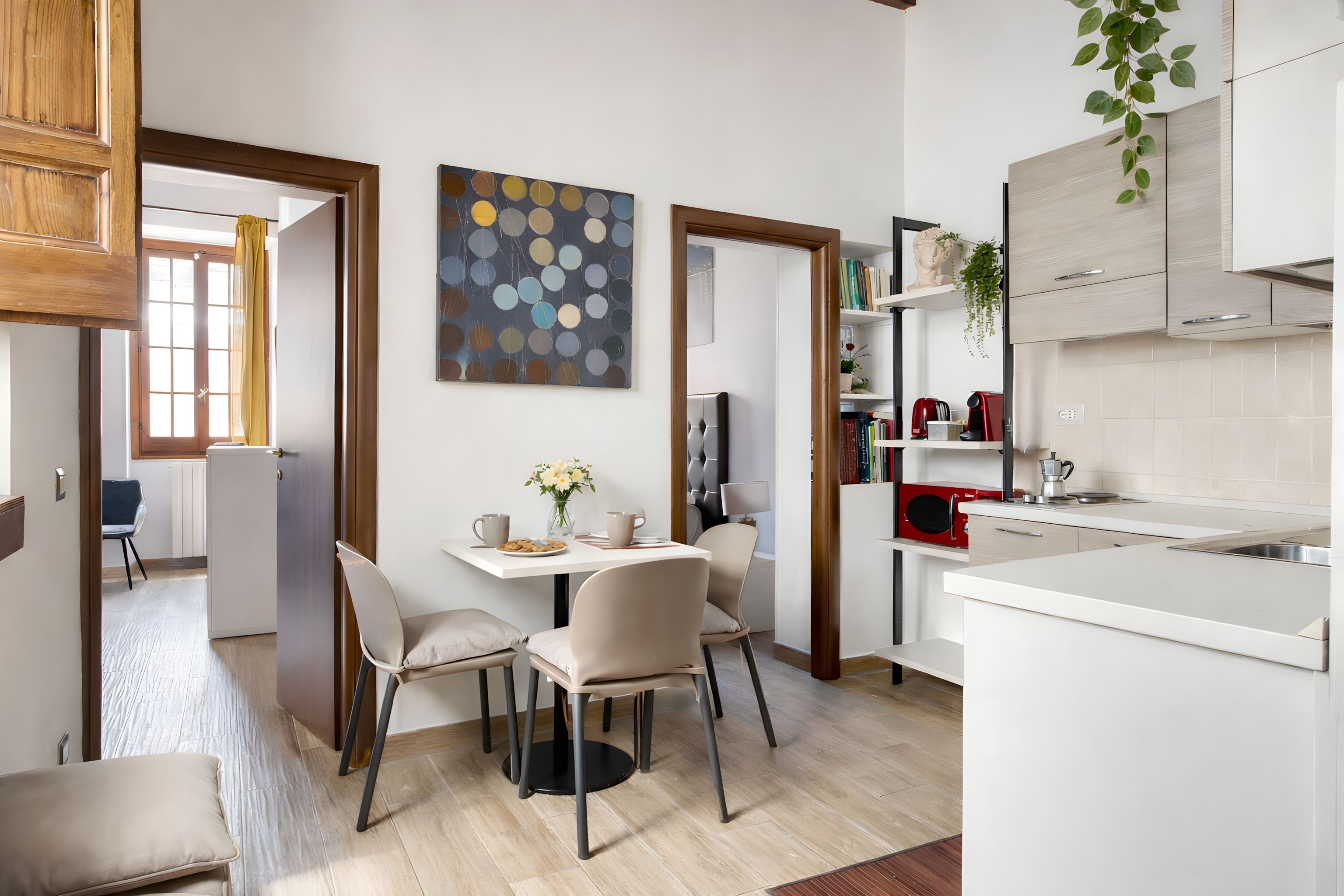 Une cuisine moderne avec un coin repas, comprenant un plan de travail blanc, une bouilloire rouge et une plante en pot.