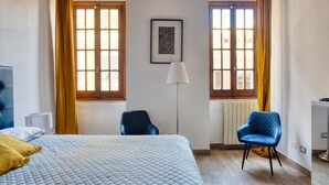A hotel room with a bed, a chair, a lamp, and two windows with curtains. - URBANA 37 MAISON   RIONE MONTI. (Roma)