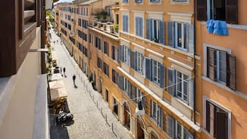Une rue pavée bordée d’immeubles à plusieurs étages, dont certains sont dotés de balcons et de volets.