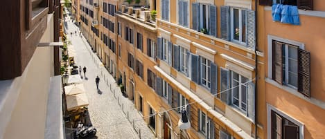 A cobblestone street lined with multi-story buildings, some with balconies and shutters.