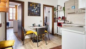 A modern kitchen with white cabinets, a dining area with two chairs and a table, and a living area with a sofa and a coffee table. - URBANA 37 MAISON   RIONE MONTI. (Roma)