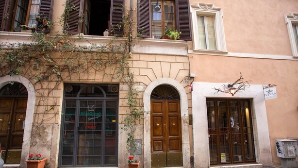 A building with three wooden doors, each with a small potted plant in front. - URBANA 37 MAISON   RIONE MONTI. (Roma)