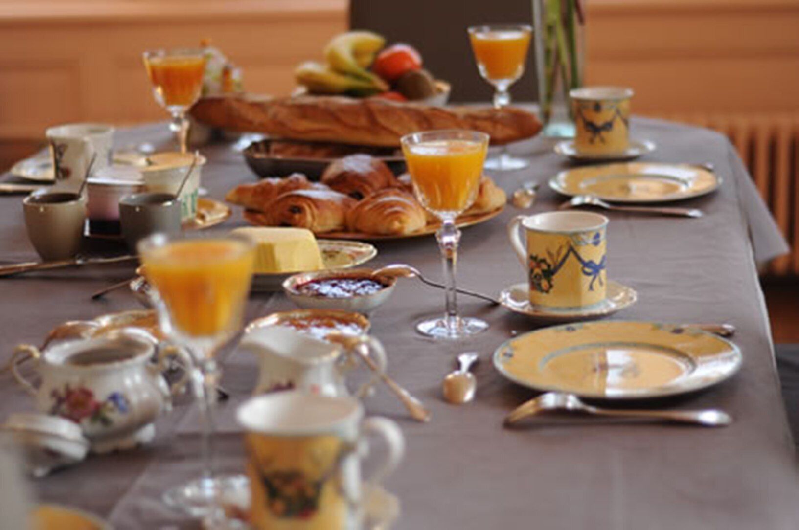 Ein Frühstückstisch gedeckt mit Croissants, Obst, Orangensaft und Kaffee.