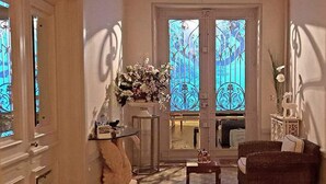 A living room with a sofa, a small table, a vase of flowers, and a door with stained glass windows.