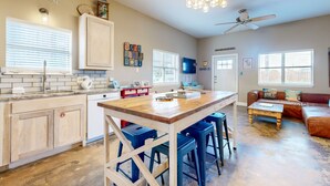 A spacious kitchen with a central island, bar stools, and a ceiling fan.