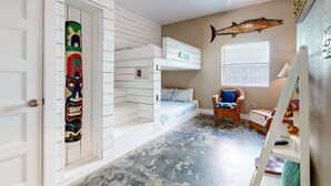 A room with a bunk bed, a ceiling fan, a window with blinds, and a decorative fish on the wall.