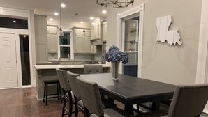 Una cocina moderna con armarios blancos, una mesa de comedor de madera oscura y cuatro sillas tapizadas.