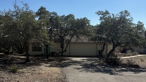 Un bâtiment doté d’une porte de garage, entouré d’arbres et bordé d’une allée en gravier.