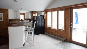 Une cabane dotée d’une cuisine, d’un coin repas et de grandes fenêtres.