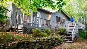 Un chalet rustique doté d’une terrasse en bois et d’un mur en pierre.