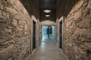 Un pasillo con paredes de piedra, suelo de baldosas y una lámpara en el techo.