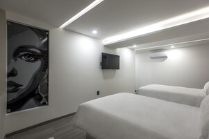 Habitación de hotel moderna con una cama grande, un televisor de pantalla plana montado en la pared y un equipo de aire acondicionado instalado en el techo.