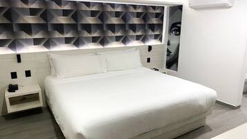 Una habitación de hotel moderna con una cama grande, una mesita de noche, aire acondicionado de pared y un cabecero con motivos geométricos.