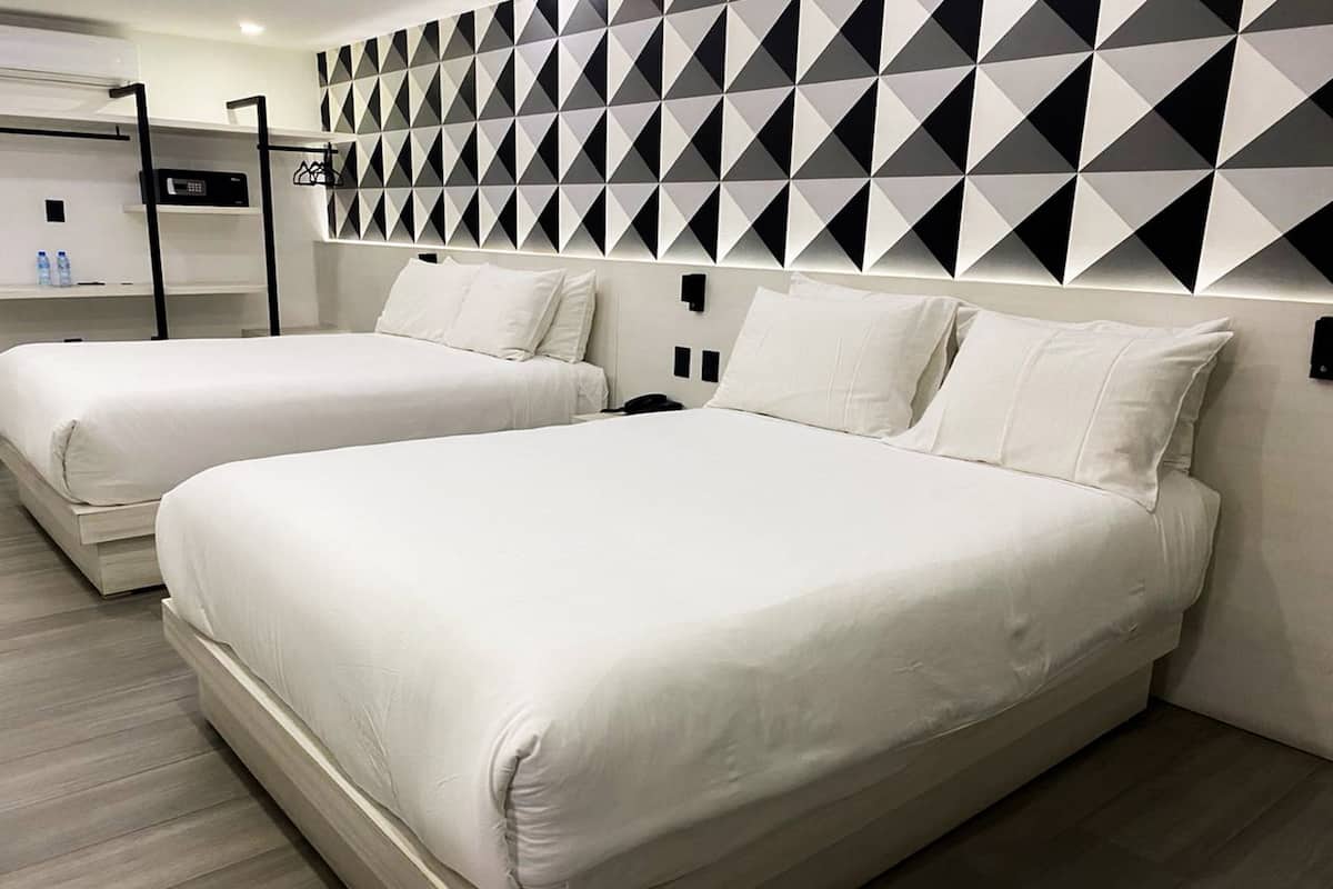 A hotel room with two beds, a geometric-patterned wall, and a modern design.