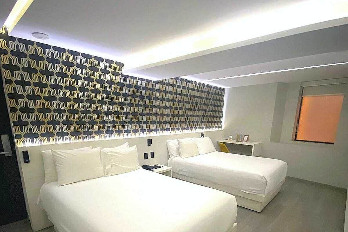 A modern bedroom with a large bed, a smaller bed, and a desk.