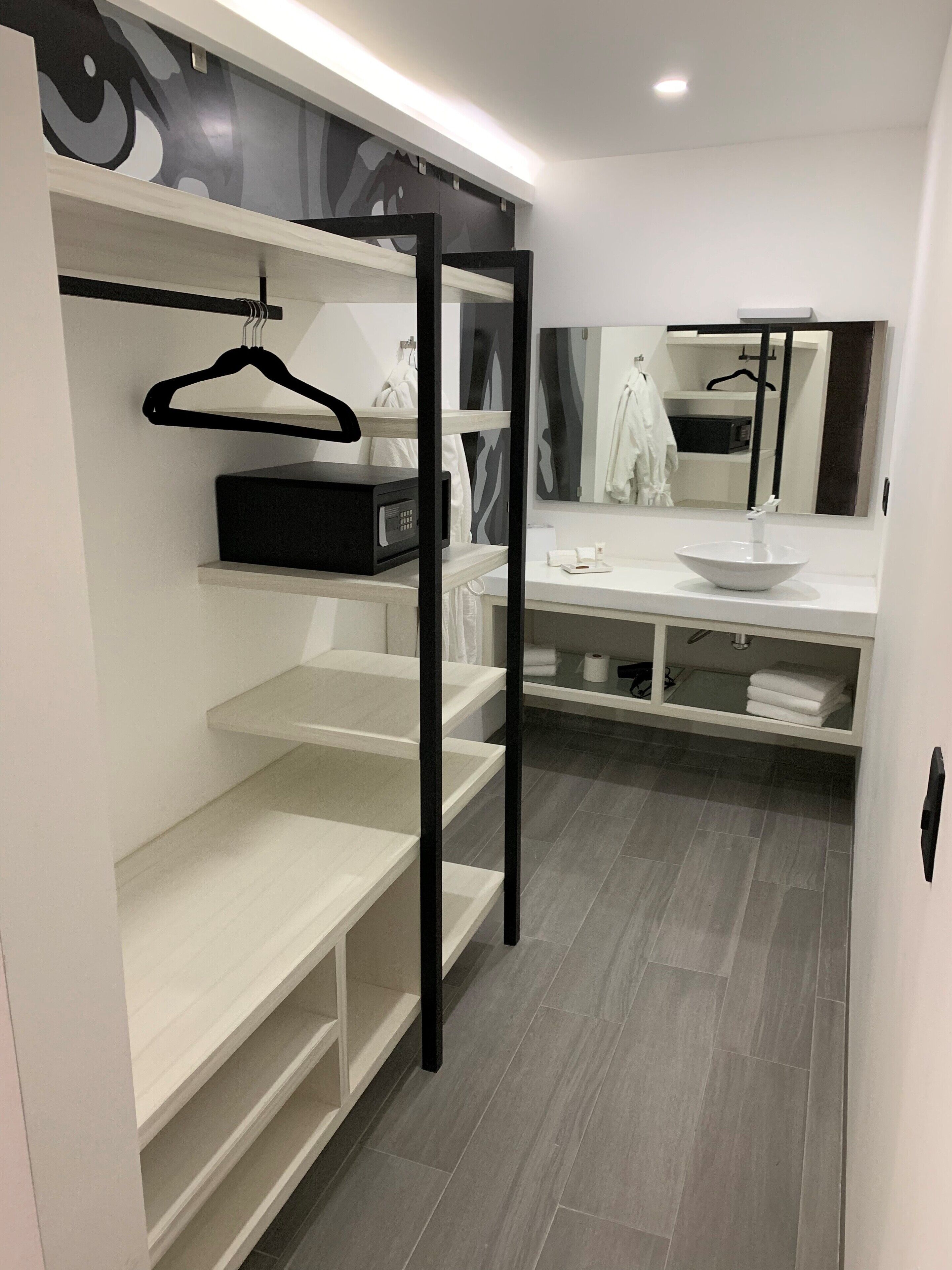 A modern bathroom with a vanity, mirror, and built-in shelves.