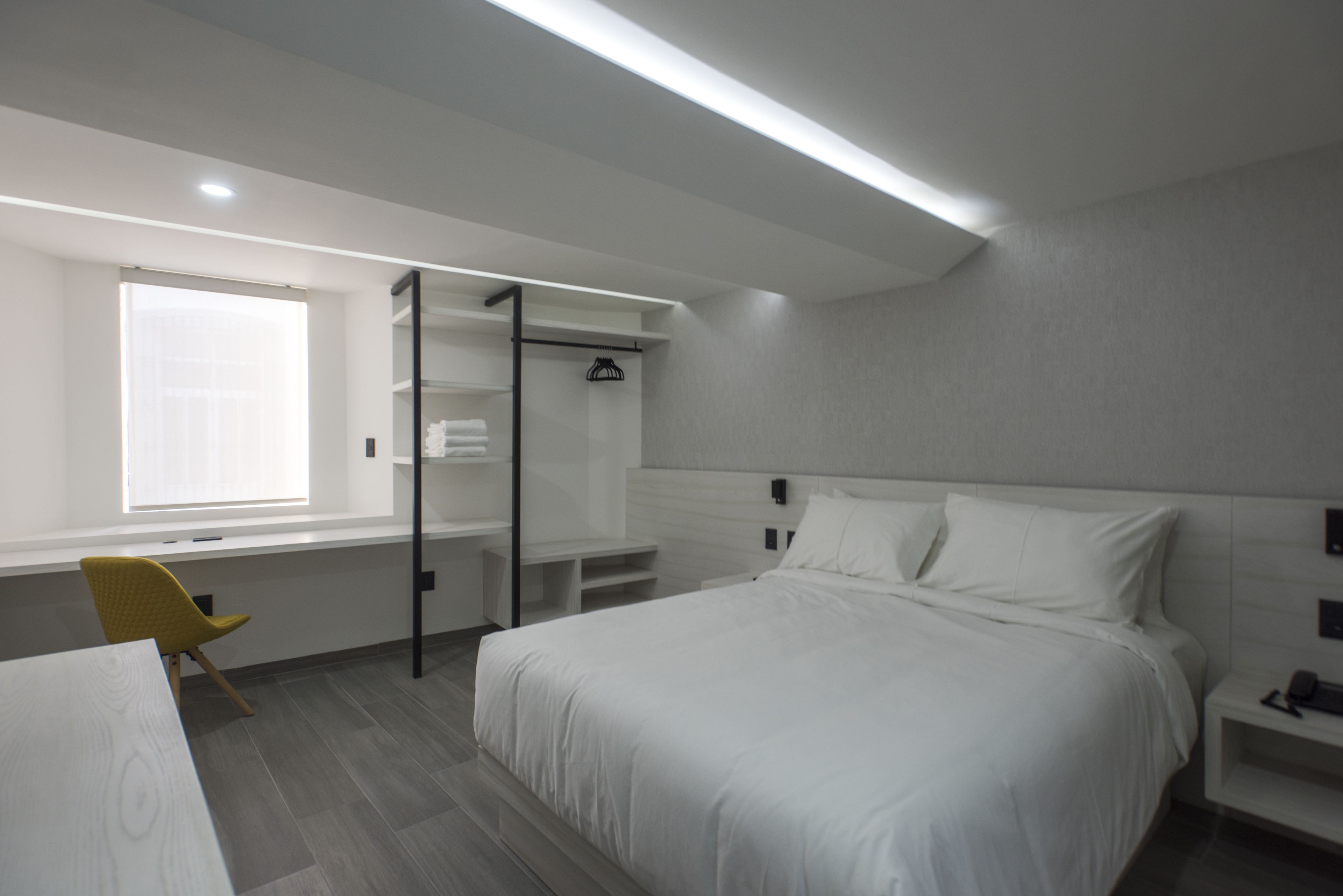 Una habitación de hotel moderna con una cama grande, un escritorio, una silla y un armario.