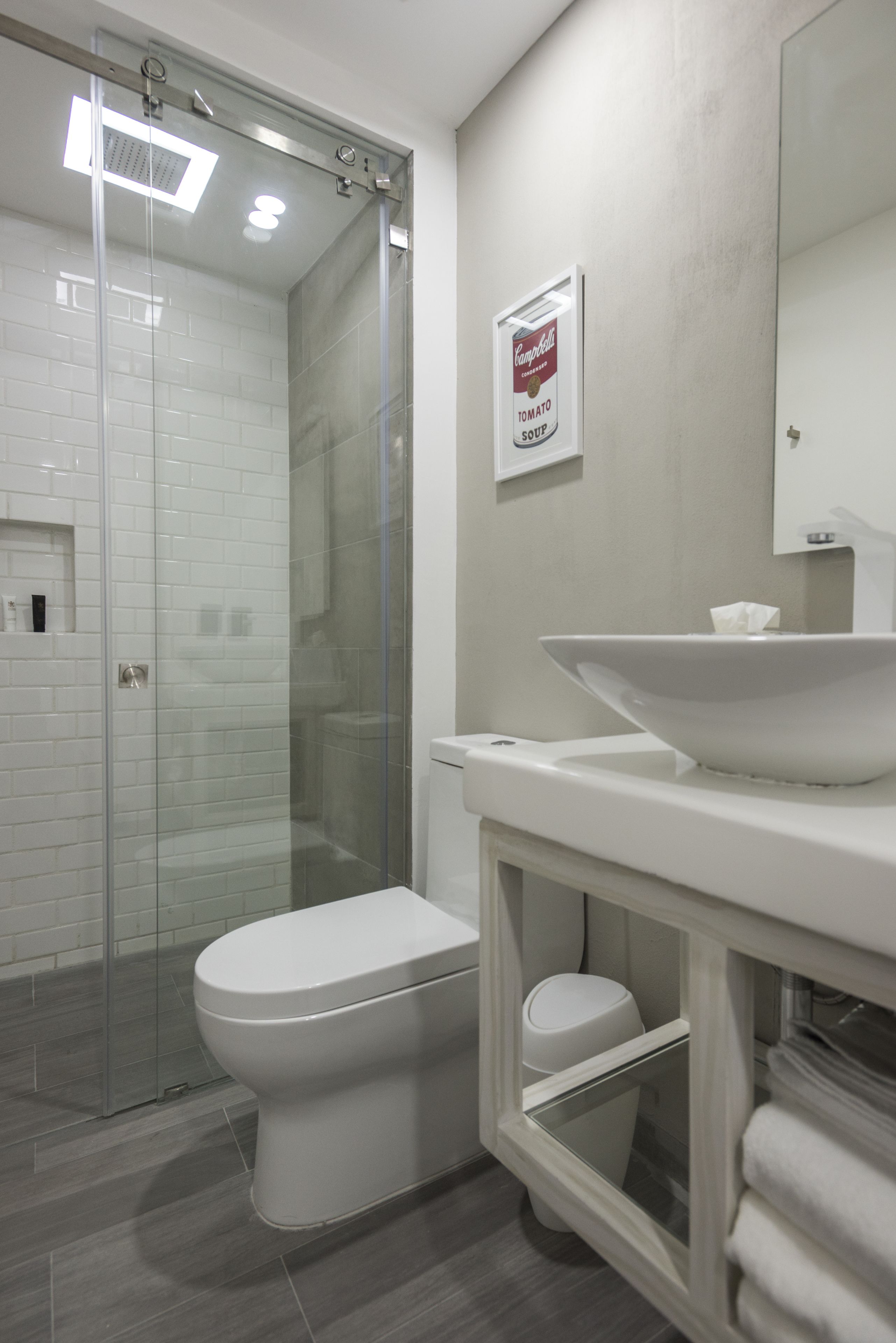 A modern bathroom with a glass-enclosed shower, a white toilet, and a sink with a towel rack.