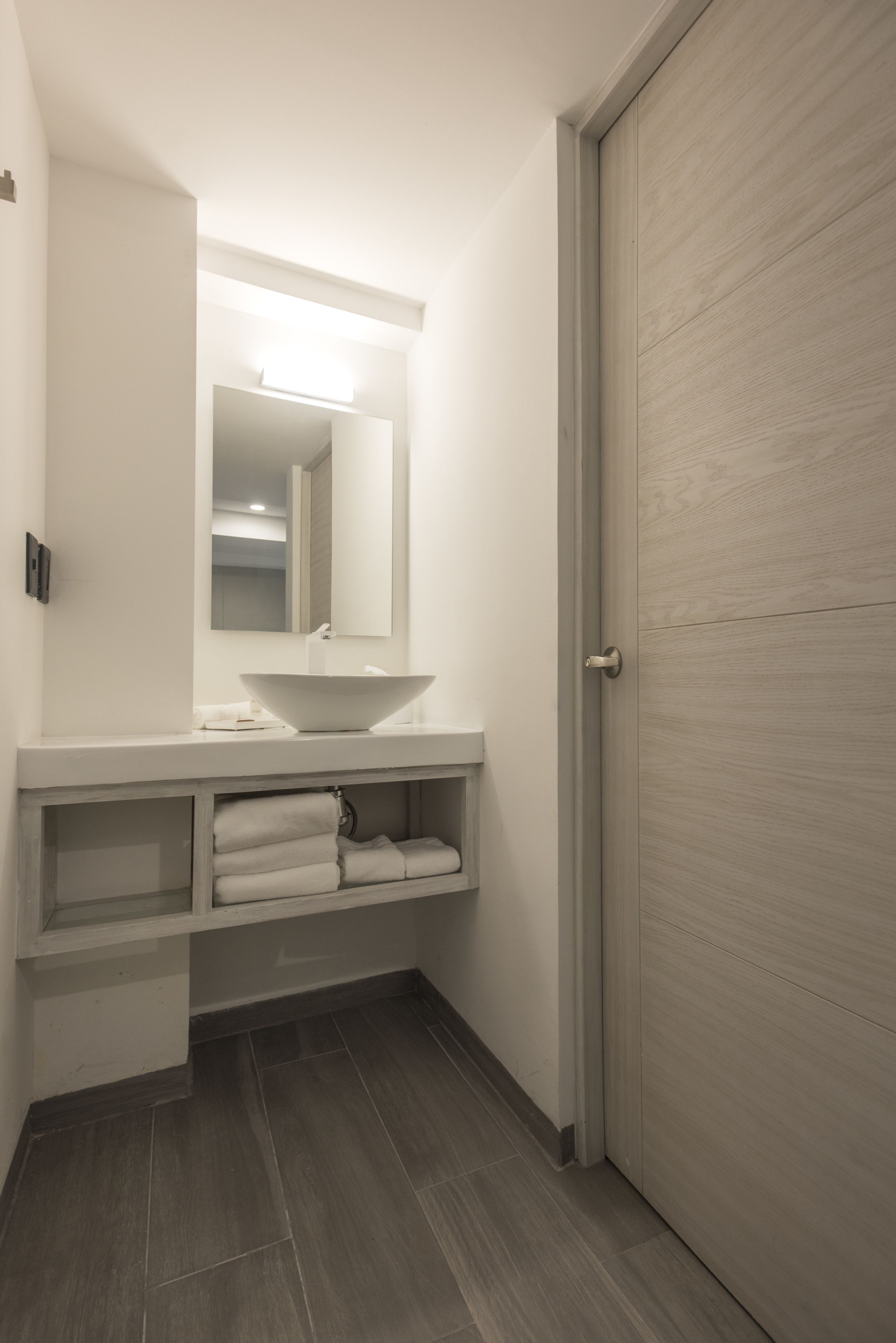 A bathroom with a white sink, a mirror, and a towel rack.
