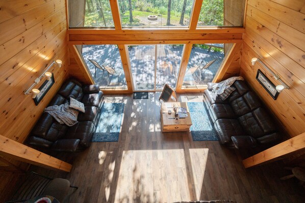 A cabin with two leather sofas, a coffee table, and a large window offering a view of a forest.
