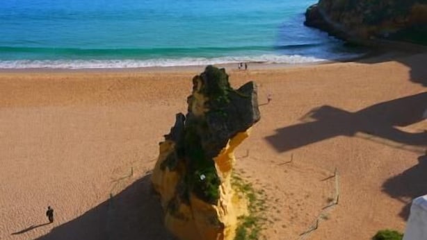 Una platja amb una roca destacada i una vista clara de l'oceà.