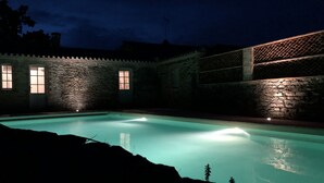 A swimming pool with stone walls and windows, surrounded by a stone fence. - Large Italian villa with its park, swimming pool and tennis court (Saint-Étienne-De-Mer-Morte)