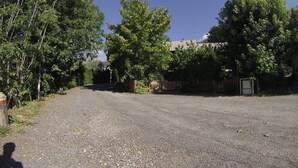Una strada sterrata conduce a un'area recintata, con alberi e un edificio sullo sfondo.