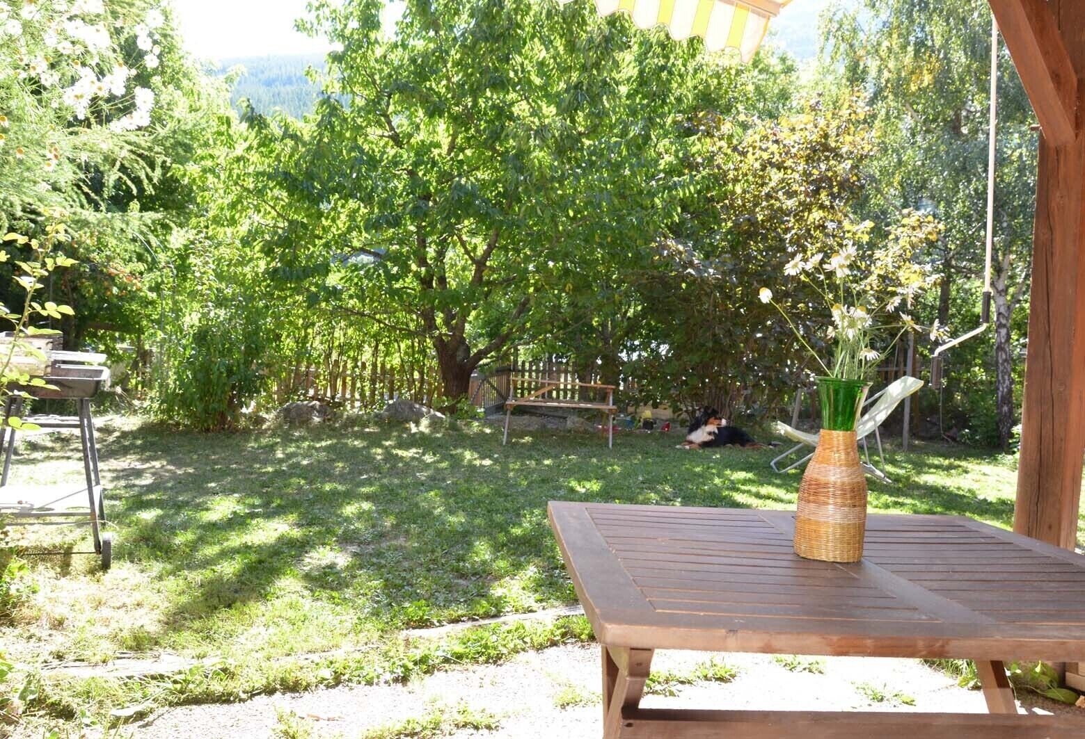 A wooden deck with a table and a wicker vase with flowers.